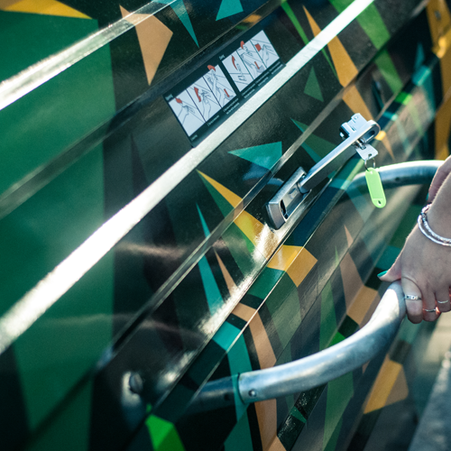 A hand grips a metal handle on the door of a Bikehangar storage container.
