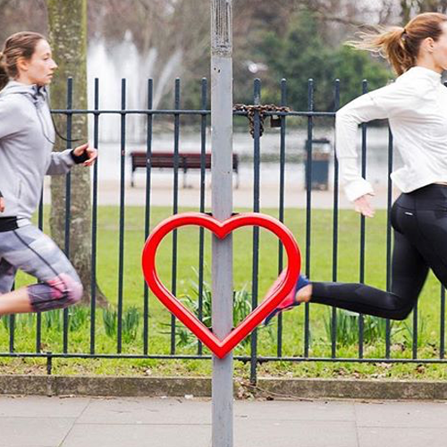 Two joggers running past a Cyclehoop Love Hoop