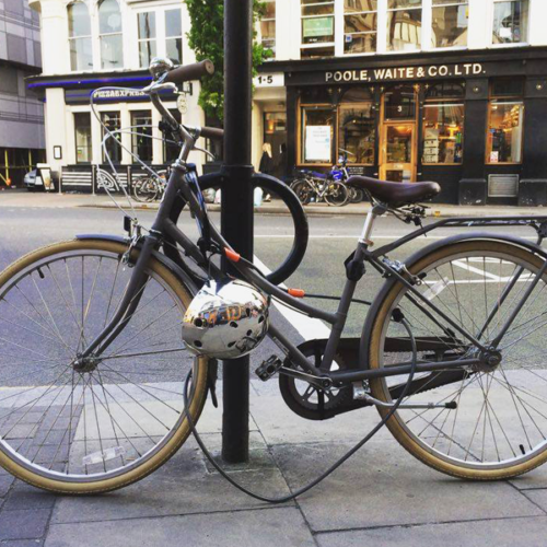A bicycle locked to a metal Cyclehoop attached to a street sign.